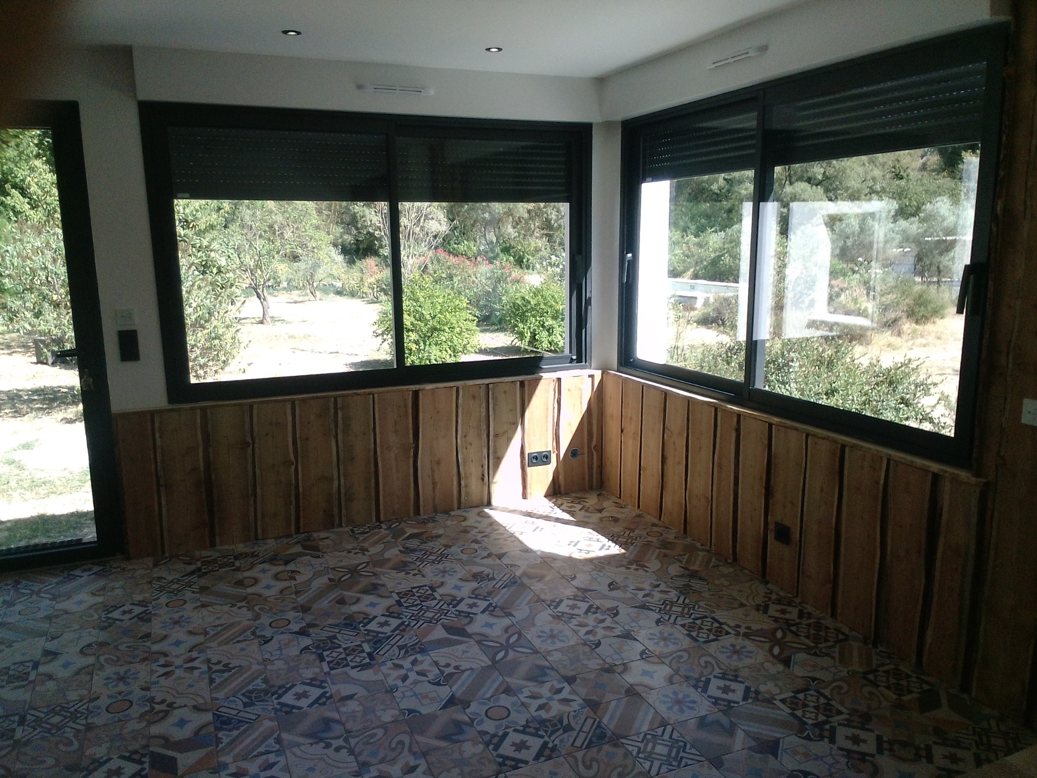 Pièce avec grandes baies vitrées et sol carrelé à motifs