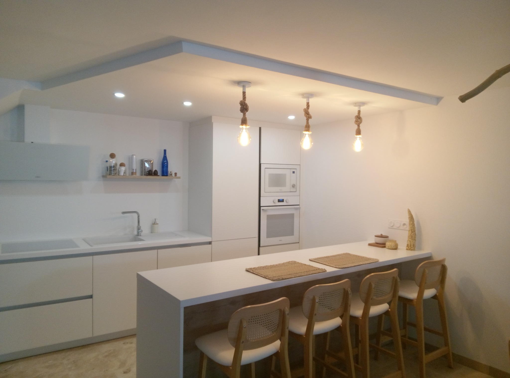 Cuisine blanche moderne avec plan bar et suspensions à ampoules